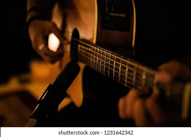 A man playing acoustic guitar in recording session with microphone  - Powered by Shutterstock