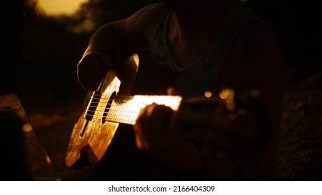 Man playing acoustic guitar at sunset - Shutterstock ID 2166404309