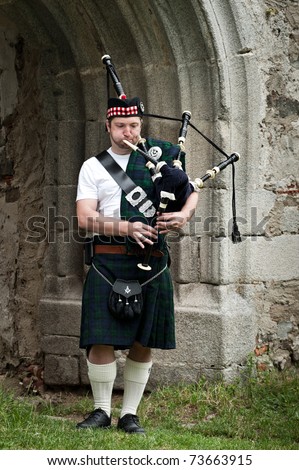 Man playing Bagpipe under an old archway