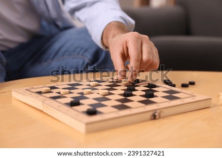 Man playing checkers at wooden table, closeup
