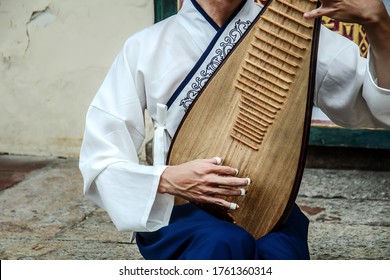 A Man Is Playing A Chinese Musical Instrument Called Pipa