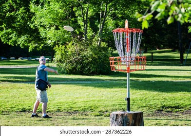 man playing disc golf in a park on a summer day