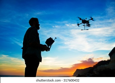man playing with the drone. silhouette against the sunset sky - Shutterstock ID 317600432