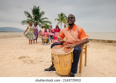 Hombre tocando un tambor en una playa.
