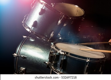 The Man Is Playing Drum Set In Low Light Background.