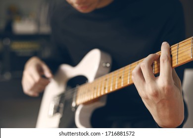 Man playing electric guitar at recording studio.