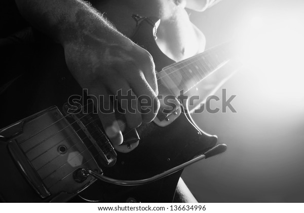 man playing\
electrical guitar in black and\
white