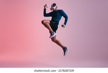 Man playing a game of kickboxing in virtual reality. Active young man jumping mid air while wearing virtual reality goggles. Sporty young man exploring immersive virtual reality games. - Powered by Shutterstock