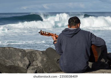 Man playing guitar in front of waves. Reunion Island - Powered by Shutterstock