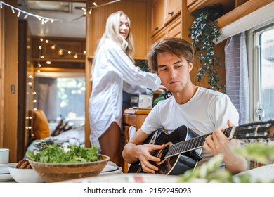 Man Playing Guitar, Singing Song On Small Kitchen,cooking In Van. Young Girl,guy Just Married Couple,lovers Traveling In Camper,house On Wheels,trailer,motor Home. Love Romantic Road Travel Vacation.