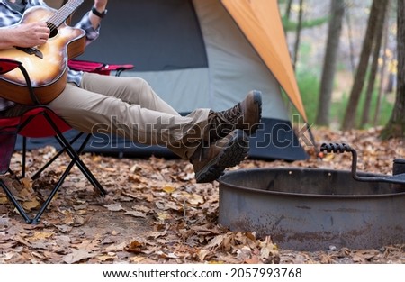 Man playing guitar while camping in fall