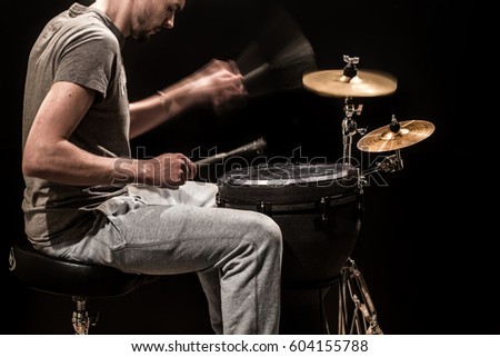 man playing a  jumbo drum and cymbals on a black background, percussion instruments with a musician and a creative musical concept