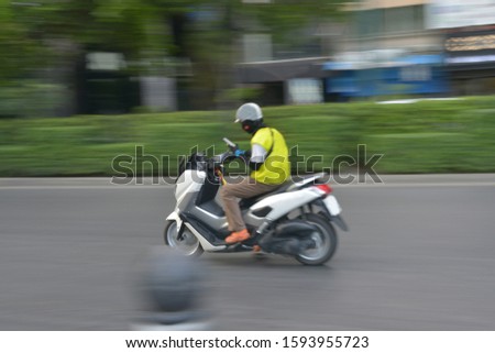 A man playing mobile while riding a motorcycle.