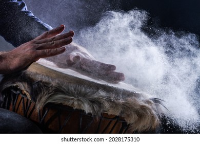 Man is playing on djembe drum, covered with talcum powder. Flour splashes on dark background. Summer festival concert performance. Ethnic rhythm. Percussion musical instruments and culture concept.  - Powered by Shutterstock