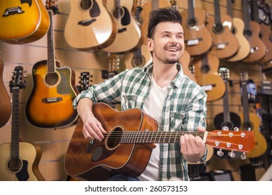 Man Is Playing On Guitar In Music Shop.