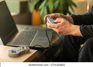 A Man Playing On His Laptop Computer With A Old School Classic Gaming Console Feeling Nostalgic At Home During Lockdown Time In 2020