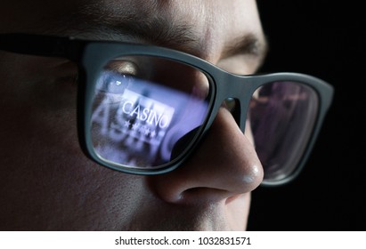 Man Playing Online Casino Games Late At Night. Gambling Problem And Addiction Concept. Addict With Reflection Of Laptop Screen On Glasses.