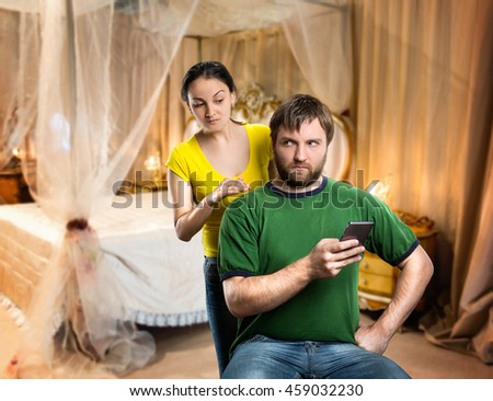 Man playing with phone, woman looking over the shoulder over black background