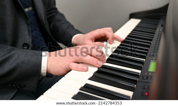 Man playing piano. Hands of young man playing electric\
piano at home.  Playing music instrument in church. Electric organ\
piano keyboard.  