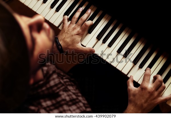 Man playing piano on\
dramatic dark stage