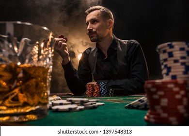 Man is playing poker with a cigar and a whiskey. A man winning all the chips on the table with thick cigarette smoke.