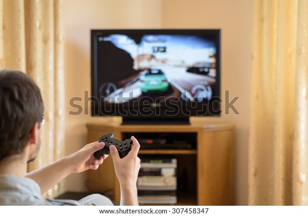 man playing racing video game on console
(television) in home - stock
photo