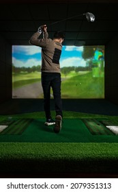 A man playing screen golf. Golf Simulator. Young golf player having playing video-game golf indoors - Shutterstock ID 2079351313