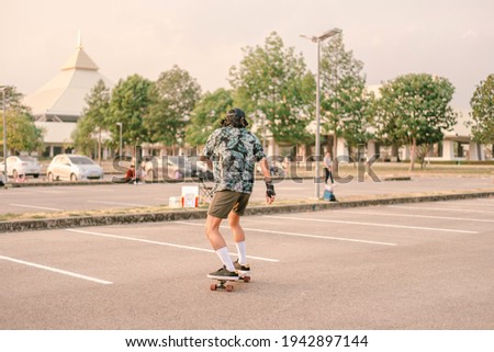 Similar – Young man riding on skate and holding surfboard