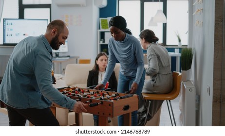 Man playing soccer game with woman at foosball table, meeting for drinks and entertainment at office after work. Multi ethnic group of colleagues enjoying beer and pizza after hours - Shutterstock ID 2146768789