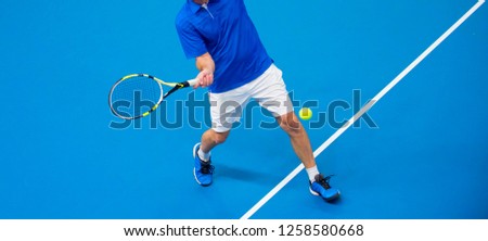 man playing tennis on blue floor