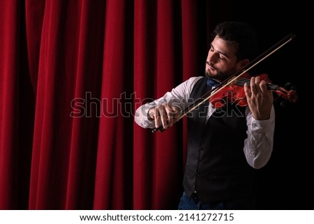 Man playing violin. Young man in theater playing violin. Violinist playing in front of his audience  Copyspace. background.