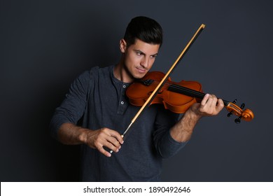 Man playing wooden violin on black background