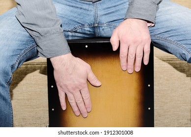 The man plays the cajon drum. Close-up view of drummer's hands while practicing percussion instrument.