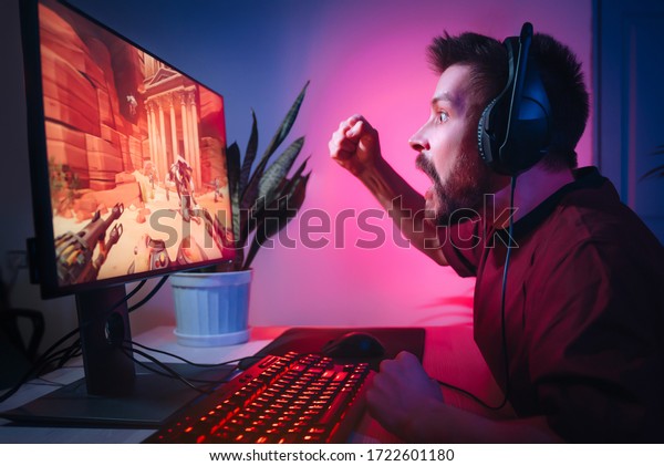 A man plays computer games at\
home. The guy is watching a video with headphones. The emotional\
player screams. Weekend at the screen. The irritated man\
lost.