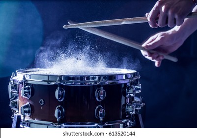 man plays musical percussion instrument with sticks closeup on a black background, a musical concept with the working drum, beautiful lighting on the stage - Shutterstock ID 613520144