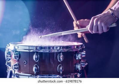 Man Plays Musical Percussion Instrument With Sticks Closeup On A Black Background, A Musical Concept With The Working Drum, Beautiful Lighting On The Stage