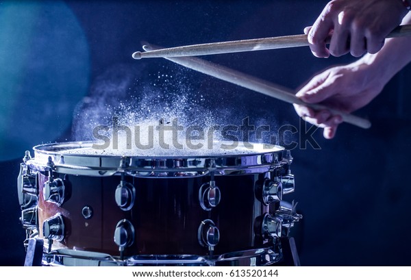 man plays musical percussion
instrument with sticks closeup on a black background, a musical
concept with the working drum, beautiful lighting on the
stage