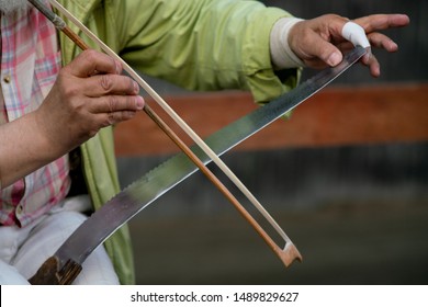 A Man Plays A Musical Saw. Close-up.