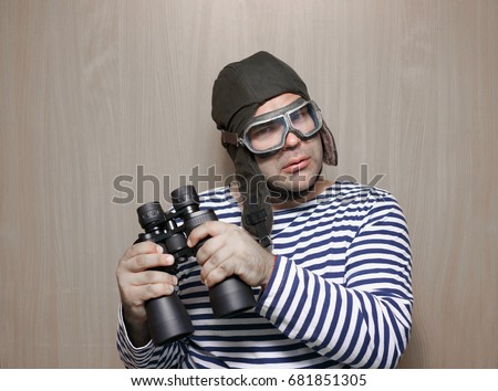 man plays the pilot, holding binoculars and surprised. Childhood. Fantasy, imagination. Retro style. serious male playing indoors on wooden background. Travel and adventure concept