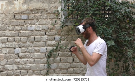 A man plays virtual augmented reality game using head mounted display and motion sensing brass knuckles