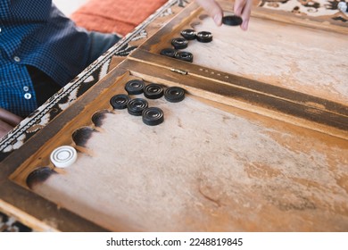 a man plays at a wooden table, backgammon