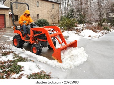 Man Plowing Snow And Ice From A Suburban Driveway