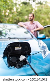 Man Plugging Cable To Electric Car