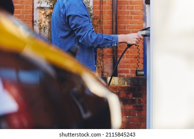 Man Plugging In Electric Car To Charging Point Outside Home On Street