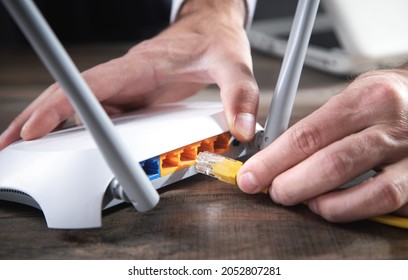 Man plugging internet cable into wifi router. - Shutterstock ID 2052807281