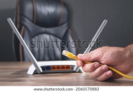 Man plugging internet cable into wifi router.