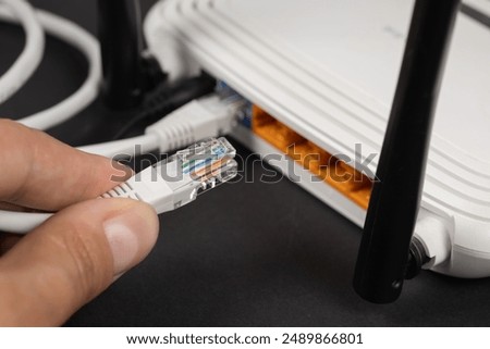 Man plugging internet cable into wi-fi router.