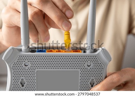 Man plugging internet cable into wifi router.