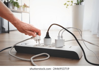 Man plugging the power plug. Electrical plug in outlet socket at home.