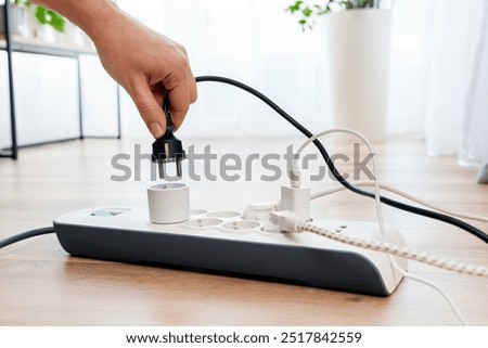 Man plugging the power plug. Electrical plug in outlet socket at home.
